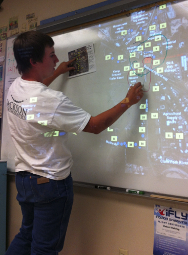 Photo of a student marking contaminated wells on a projected map image.