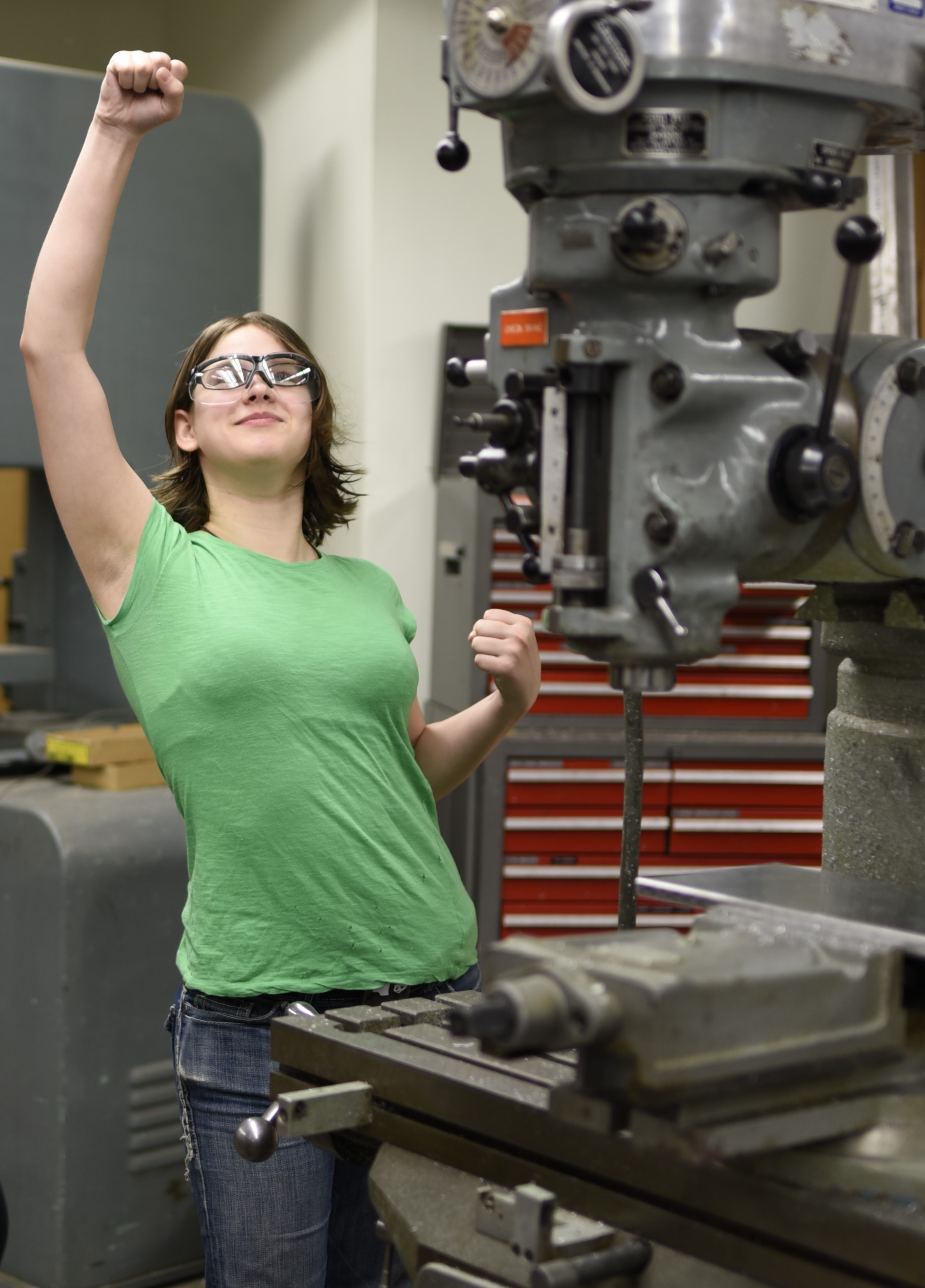 andrea raises her hand in victory behind the mill in the machine shop