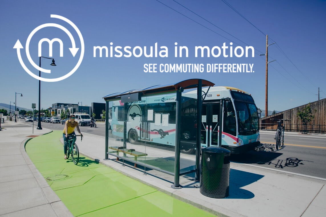 a biker rides on a protected bike line next to a bus stop with a bus parked. Missoula in motion logo is displayed.