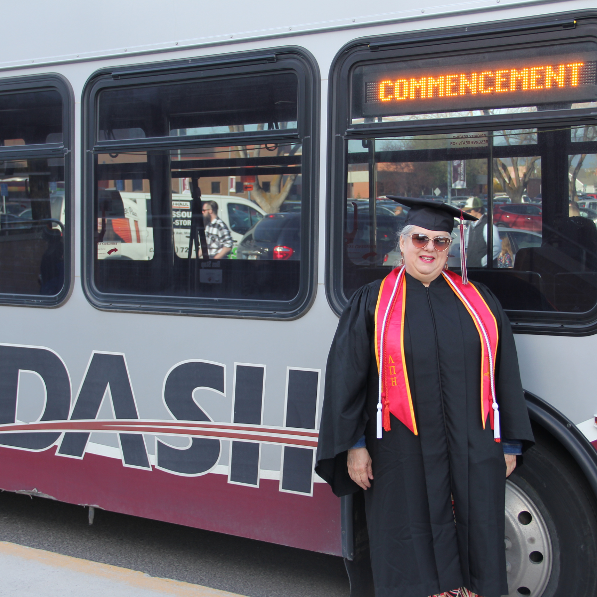 Graduating senior standing in front of UDASH bus